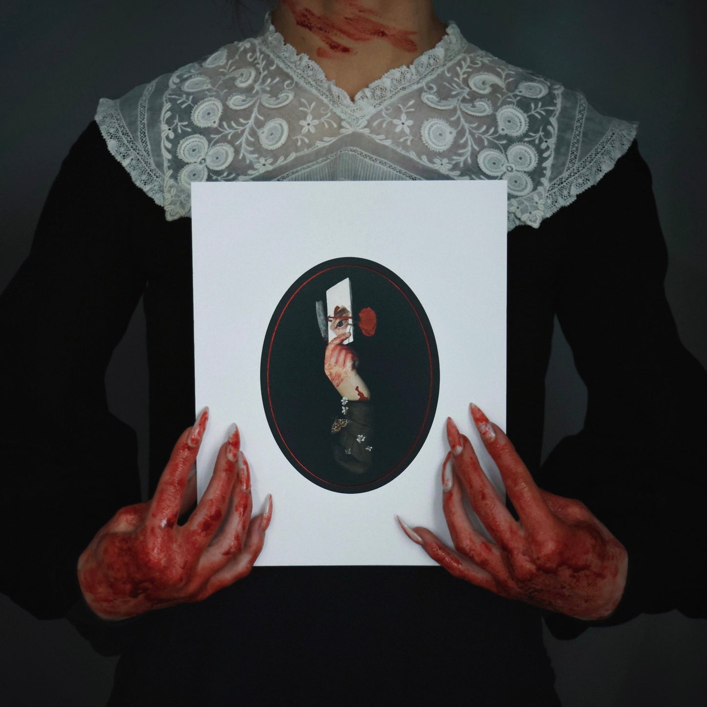 Bloody woman in a Victorian dress with long fingernails holds a gothic collage art print featuring a bloody hand with a razor, a note, and an eye.